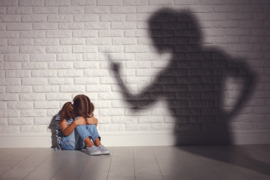 domestic violence. angry mother scolds   frightened daughter sitting on floor